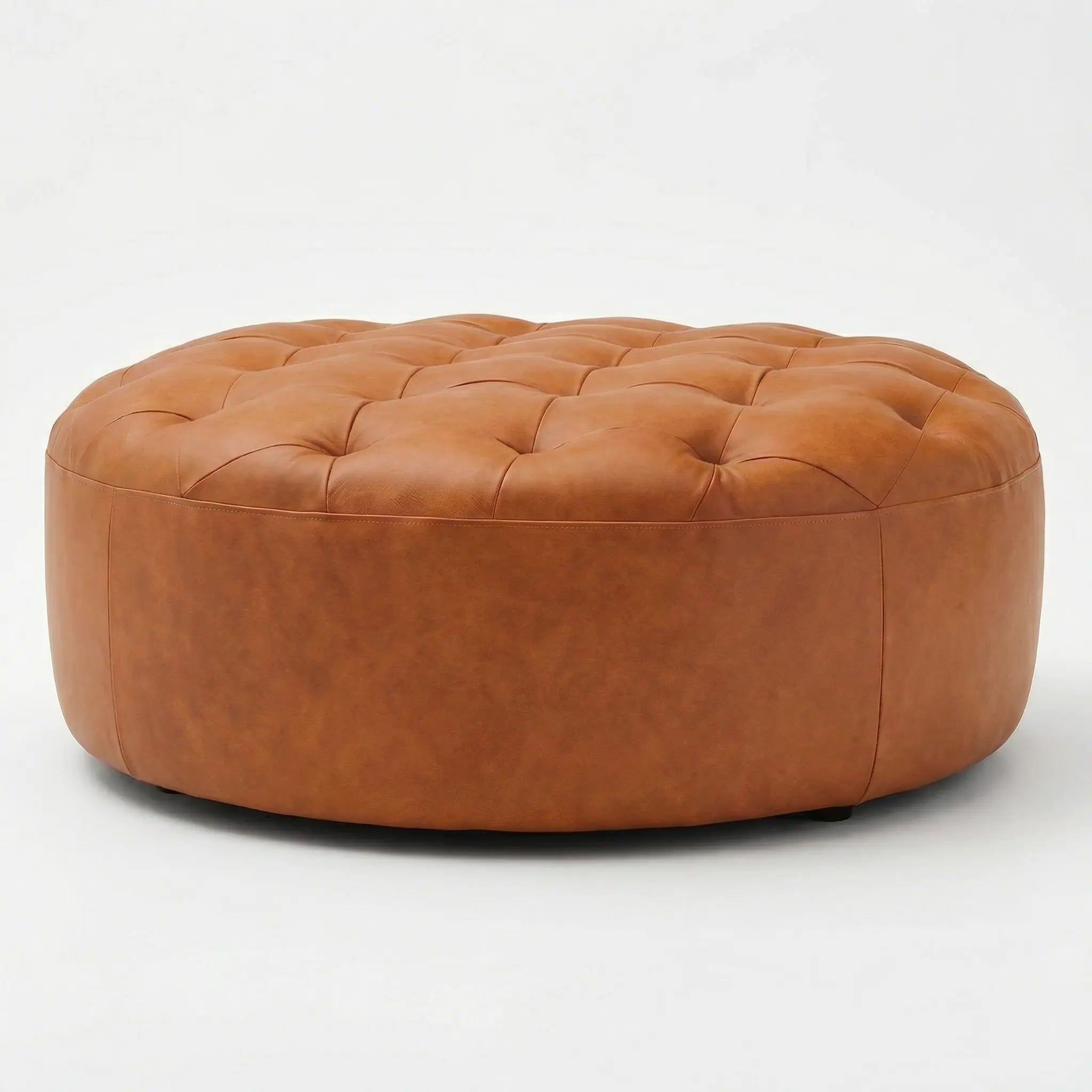 Moroccan Leather Pouf Tan leather ottoman in a living room setting with a beige sofa and plant.