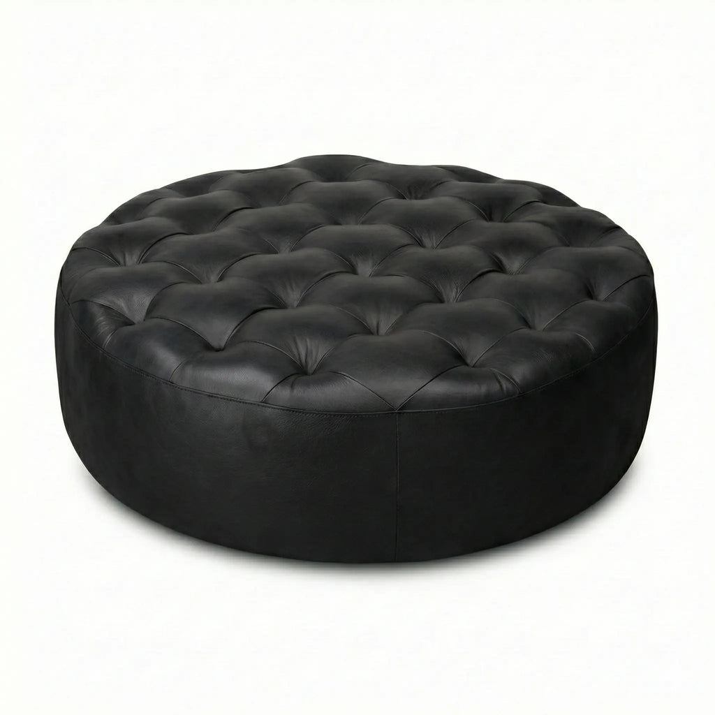Moroccan Leather Pouf black leather ottoman in a living room setting with a beige sofa and plant.