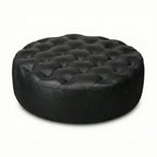 Moroccan Leather Pouf black leather ottoman in a living room setting with a beige sofa and plant.