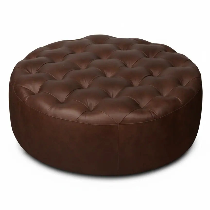 Moroccan Leather Pouf Dark Brown leather ottoman in a living room setting with a beige sofa and plant.